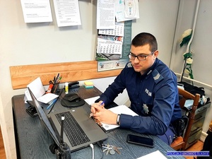 policjant umundurowany siedzi przy burku przy komputerze w pomieszczeniu biurowym