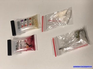 na jasnej powierzchni 4 woreczki foliowe. Jedne z napisem marihuana i czerwoną zawartością, drugi z napisem amfetamina i żółtą zawartością, trzeci z zielonym suszem, czwarty z białymi kształtkami
