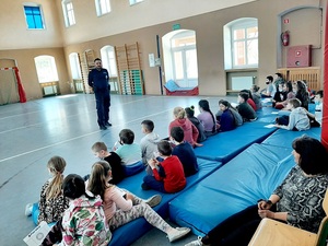 umundurowany policjant w szkole przeprowadza zajęcia profilaktyczne
