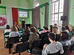 policjant umundurowany sala, siedząca młodzież, flagi ekran