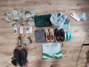 buty, różance, szara torba, pamiątki, chusteczki i inne rzeczy leżące na drewnianym blacie/podłodze