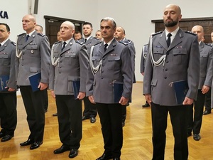 policjanci w mundurach wyjściowych stoją w pomieszczeniu podczas uroczystej zbiórki