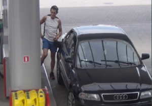 mężczyzna w koszulce na ramiączkach nalewa paliwo do baku czarnego samochodu Audi na stacji paliw
