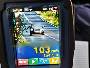pomiar prędkości na fotoradarze, wyświetlaczu 103 km/h, oraz samochód ciemny Audi przód