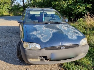 samochód ford niebieski, na masce jasne plamy, dzień, droga szutrowa