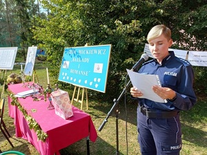 policjanta stoi na trawie w dzień przy mikrofonie w tle plansze