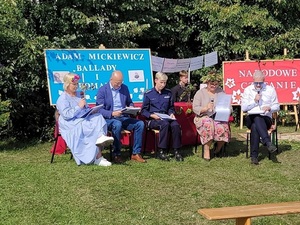 osoby siedzące na krzesłach na trawie w tle plansze