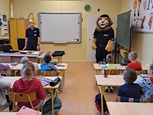 spotkanie policjanta z dziećmi w szkole, dzieci siedzą w ławkach policjant stoi , Komisarz Lew