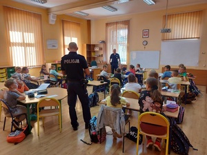 spotkanie policjanta z dziećmi w szkole, dzieci siedzą w ławkach policjant stoi ,