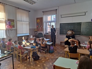 spotkanie policjanta z dziećmi w szkole, dzieci siedzą w ławkach policjant stoi , Komisarz Lew