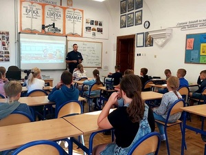 spotkanie policjanta z dziećmi w szkole, dzieci siedzą w ławkach policjant stoi