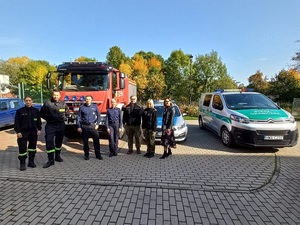 przedstawiciele służb mundurowych stoją na dworze przy pojazdach