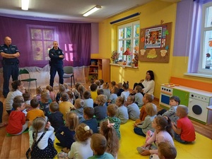 policjant stoi, dzieci, przedszkolaki siedzą