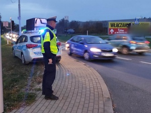 umundurowany policjant, zmierzch, droga  i jadące pojazdy
