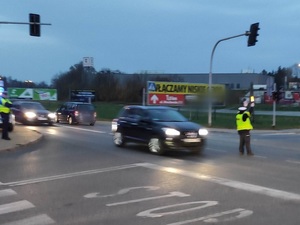 umundurowany policjant, zmierzch, droga  i jadące pojazdy