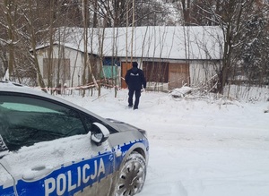 policjant przed ośnieżonym budynkiem