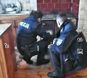dwóch umundurowanych policjantów rozpala w piecu