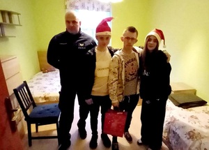 policjant umundurowany z młodzieżą w mikołajowych czapkach