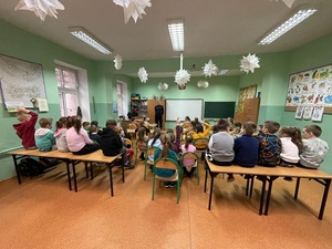 policjant umundurowany stoi naprzeciwko dzieci siedzących w klasie