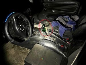 wnętrze samochodu osobowego, czerwonym śladem zaznaczona butelka piwa