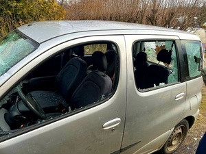 samochód osobowy koloru jasnego, widok z boku z wybitymi szybami