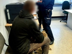 widok na mężczyznę siedzącego w pomieszczeniu w ciemnej bluzie i jasnych spodniach