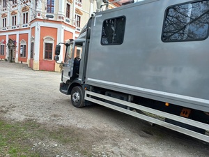 pojazd duży, koloru szarego, stojący na przeciwko budynku