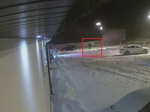 sylwetka mężczyzny oznaczona na czerwono, na zaśnieżonym parkingu w nocy
