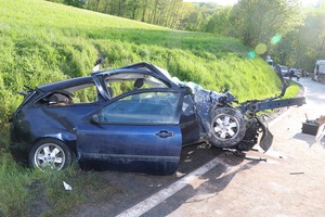 uszkodzony samochód osobowy koloru ciemnego na drodze , światło dzienne