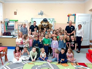 dwóch policjantów umundurowanych oraz maskotka komisarz Lew na spotkaniu z dziećmi