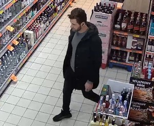 mężczyzna w ciemnej dłuższej kurtce na terenie sklepu spożywczego