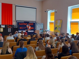 policjant przemawia na sali, na krzesłach tyłem siedzi młodzież