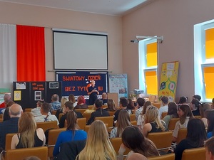 policjant przemawia na sali, na krzesłach tyłem siedzi młodzież