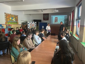 policjant rozmawia z dziećmi siedzącymi przy stołach