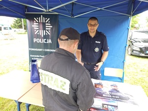 Policjant wręcza ulotkę informacyjną strażakowi