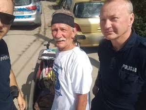 2 policjantów z mężczyzną, w tle radiowóz