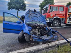 droga, niebieski samochód osobowy z uszkodzonym przodem, straż pożarna