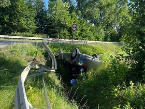 samochód osobowy leżący na dachu w przydrożnym rowie
