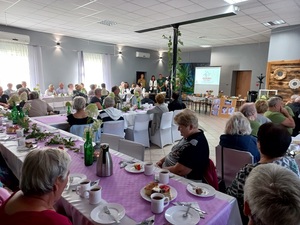 seniorzy siedzą przy stołach na spotkaniu w świetlicy wiejskiej w Laskach