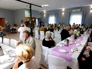 seniorzy siedzą przy stołach na spotkaniu w świetlicy wiejskiej w Laskach