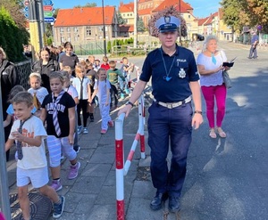 działania ząbkowickich policjantów szkole podstawowej nr 2 w Ziębicach w ramach akcji bezpieczna droga do szkoły, policjant ruchu drogowego z dziećmi przy ulicy