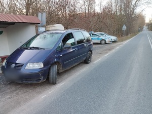 samochód VW Sharan koloru ciemnego zatrzymany przy drodze, w tle stoi radiowóz oznakowany