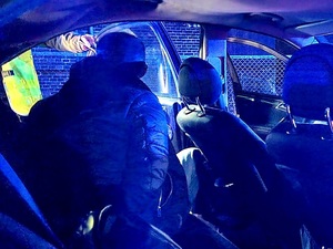 zatrzymanie nietrzeźwego kierującego, widok w środku pojazdu osobowego na tylnym siedzeniu zatrzymany widoczny z tylu, noc