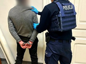 zatrzymany za kradzież zuchwałą mężczyzna w kajdankach trzymany przez umundurowanego policjanta