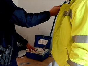 nietrzeźwy mężczyzna badany alkomatem w komendzie przez umundurowanego policjanta