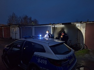 nocne licznie bezdomnych, przy garażach policjanci umundurowani przy radiowozie