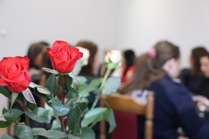róże na pierwszym planie , w tle kobiety siedzące przy stołach