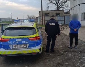 zatrzymany nietrzeźwy rowerzysta mężczyzna przez umundurowanego policjanta , na zdjęciu stoją obok oznakowanego radiowozu.