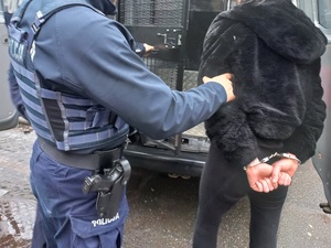 zatrzymana oszustka z umundurowanym policjantem przy klatce oznakowanego radiowozu