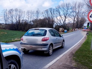 samochód peugeot koloru srebrnego zatrzymany na drodze , za nim stojący oznakowany radiowóz